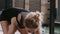 Close-up young attractive athletic blonde woman exercising with battle rope, stopping to rest after workout in large gym