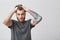 Close up of young attractive red-haired unhappy man with stylish haircut and beard holding hair with hands, looking in