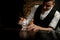 Close-up young bartender holds tweezers with ice cube and puts it in steaming glass