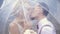 Close-up, Young beautiful newlyweds kiss under a transparent umbrella. spring sunny day. wedding