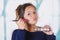 Close up of young beautiful woman holding a make up palette and doing crazy make-up in her face using a brush, in a