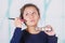 Close up of young beautiful woman holding a make up palette and doing crazy make-up in her face using a brush, in a