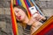 Close up of young beautiful woman sleeping in a hammock with her mouth open, while she is with a cellphone in her hands