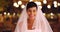 Close up of young bride standing in outdoor setting with bokeh lights, smiling