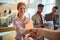 Close-up of a young business woman who is handshaking while standing in the hallway with colleagues. Business, people, company