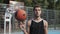 Close Up of Young Caucasian Basketball Player Wearing Black Singlet Spinning the Ball on his Finger Standing at Street