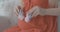 Close-up of young Caucasian female hands holding baby booties and imitating stepping on pregnant belly. Unrecognizable