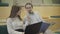 Close-up of young Caucasian man and woman sitting with laptop and documents and talking. Coworkers discussing business