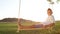 CLOSE UP Young child relaxing on wooden swing at sunset,posing for the camera.