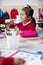 Close up of young Chinese schoolgirl wearing school uniform sitting at a desk in an infant school classroom, selective focus, vert