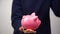 Close up of young entrepreneur inserting coin into piggy bank. Financial education for kids