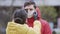 Close-up of young europeans woman put on protective disposable medical face mask on her boyfriend, outdoors. New coronavirus COVI