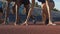 Close-up of young female athletes preparing to run at starting line, slow-motion