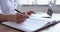 Close up young female doctor writing notes in registration album.