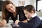 Close up of young female teacher sitting at desk with a Down syndrome schoolboy using a tablet computer in a primary school classr