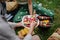 A close-up of young friends putting corn and skewers on grill and having barbecue when camping in campground.