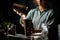 Close-up. Young girl at bar pours drink from one metal cup to another