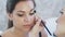 Close-up of a young girl came to the makeup studio in beauty studio. Makeup artist carefully paints the eyes of a