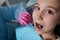 A close-up of a young girl getting a dental exam by dentist and using dental mirror to see baby teeth and gums.