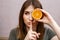 close-up of a young girl with half an orange. the girl holds a piece of orange near her face at eye level and with a finger near