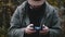 Close-up young happy casual Caucasian bearded operator man is controlling drone aircraft with remote in autumn forest.