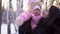 Close-up of young happy mother with cheerful child in winter outdoors. Baby girl in pink jumpsuit smiling in mom`s hands