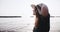 Close-up young happy smiling travel blogger woman in summer hat spinning, posing at golden sunrise sea beach slow motion