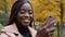 Close-up young happy woman standing in autumn park communicates video chat on smartphone friendly online conversation