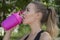 Close up of young healthy female wearing black exercise clothing drinking from pink shaker