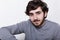 A close-up of young hipster with beard and moustache dark clever eyes isolated over white background having rest indoors looking t