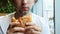 Close-up of young hungry man eats hamburger in a cafe, fast food restaurant
