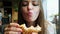 Close-up of young hungry woman eats toast in a cafe, fast food restaurant