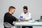 Close-up of young indian doctor in white coat injecting the patient`s hand at the table at hospital