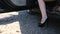 Close-up of young lady in spotted dress getting out of car and walks by road. Low angle view with focus on woman\'s legs