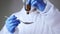 Close-up of young male doctor in the protective suit using drops medicine for patient treatment.