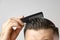 Close up young man brushing his hair with a plastic comb. Styling hair after barbershop. Hair healthcare. Lost of hair