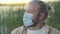 Close-up of young man in face mask admiring sunset in summer evening. Portrait of romantic thoughtful Caucasian guy