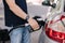 Close-up of young man refuelling a car at a petrol station. Middle selection of human hand hold fuel pump