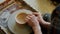 Close-up of young man`s hands molding clay into ceramic bowl on throwing wheel