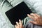 Close up of a young man on the sofa touching the black screen of a digital tablet. Person works on a tablet at home. Lying man