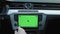 Close-up of young man using navigation app on mounted mock-up greenscreen inside modern car. Man driving car in the