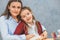 Close-up of a young mother and daughter sitting on a gray background. During this, my mother hugged her daughter and