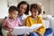 Close up of young mother sitting on sofa in the living room with her children, reading them a book, low angle