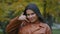 Close-up young pretty hispanic woman standing in park posing outdoors looking at camera showing hand gesture phone near