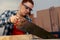 close-up of a young red-haired woman carpenter sawing a wooden board with a saw, in her small carpentry shop.