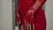 Close-up of a young slender woman trying on a red evening dress in an atelier.