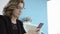 Close-up of young smiling woman typing an sms message via smartphone device at home interior, cheerful caucasian girl