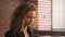 Close up of a young stylish businesswoman working on a laptop in a loft apartment with red brick wall