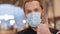 Close up young stylish hipster guy in protective face mask show thumb up like gesture. Prevention of coronavirus COVID