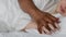 Close up of young unrecognizable woman sleeping in bed, african american boyfriend touching her hand in morning